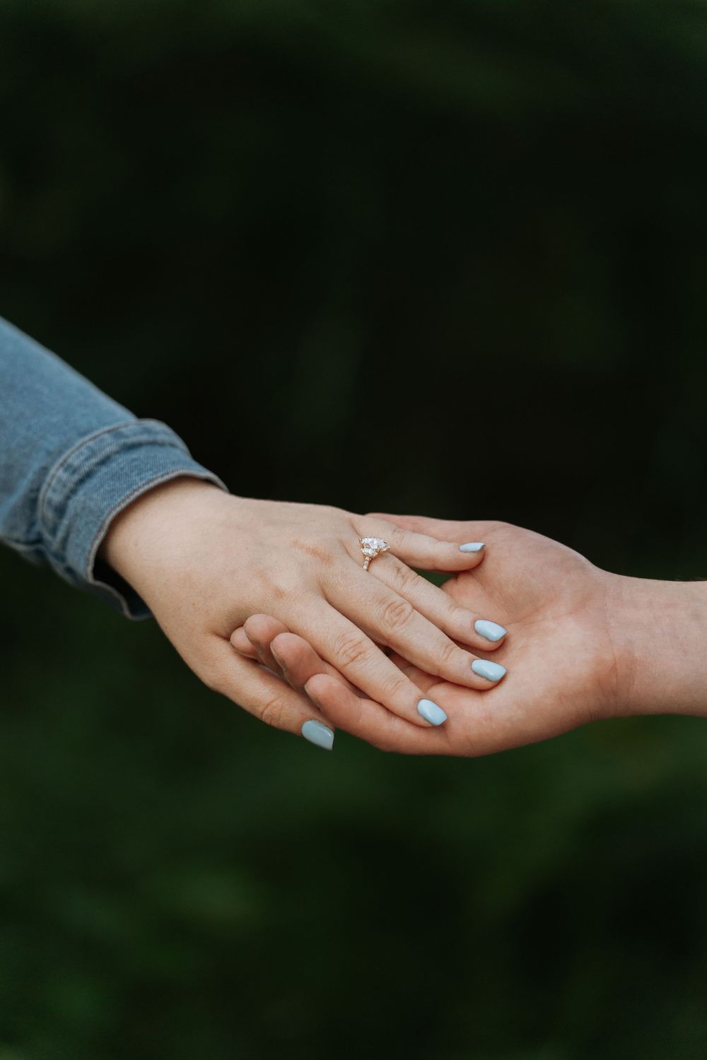 A couple's hands resting together, one wearing an engagement ring